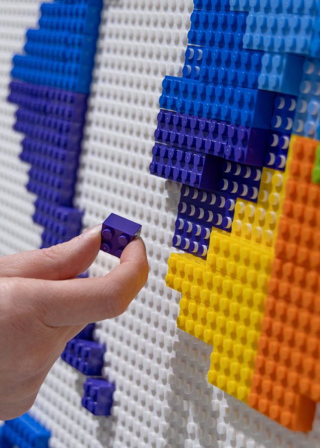 An attendee placing a single large brick into the Osceola County logo mosaic
